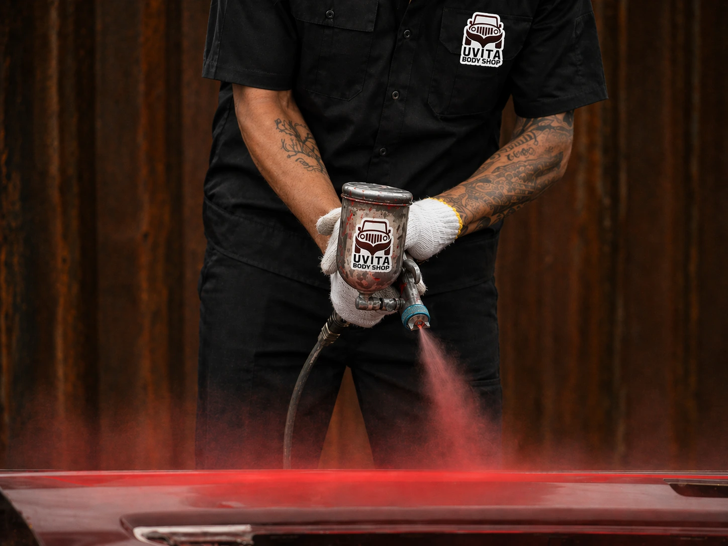 Técnico de Uvita Body Shop pintando un vehículo con pistola HVLP en la cabina controlada